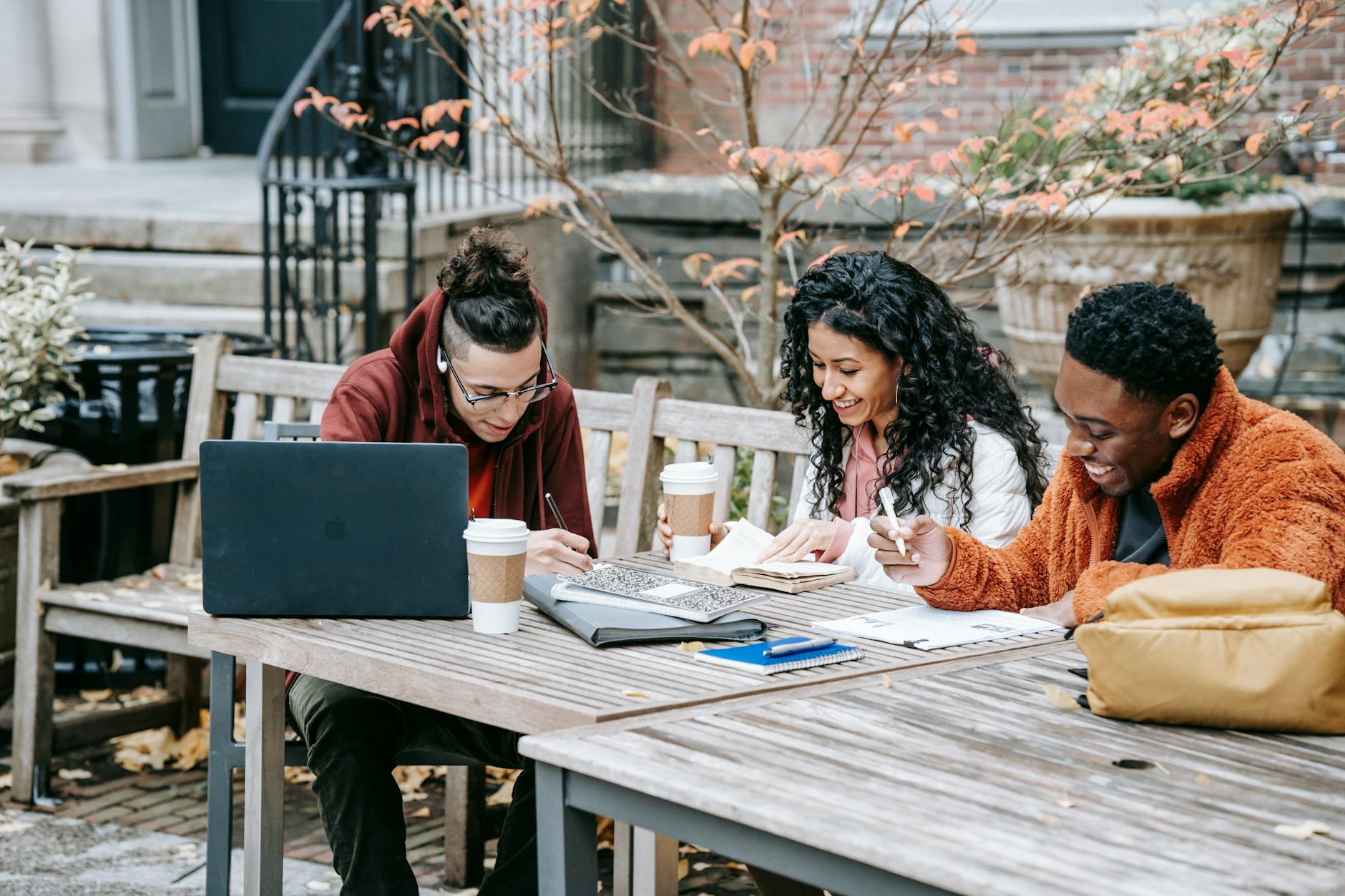 cheerful multiethnic students studying at table on terrace